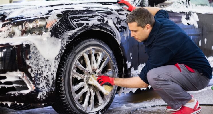 Man worker washing car's alloy wheels on a car wash